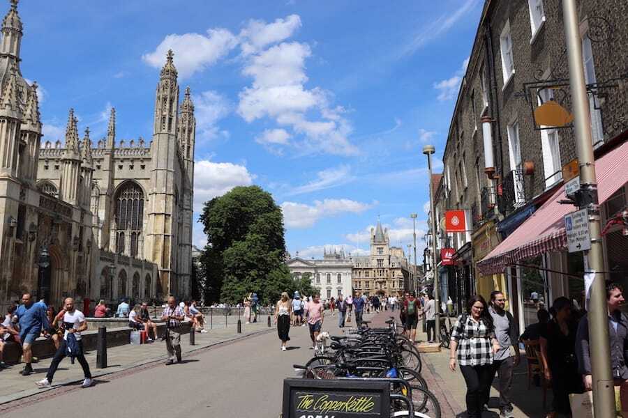 Shoppers and cyclists on King's Parade in Cambridge, with King's College Chapel against a blue sky