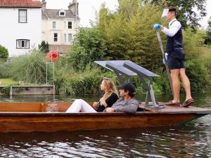 the back of a punt with a chauffeur wearing a protective mask and gloves