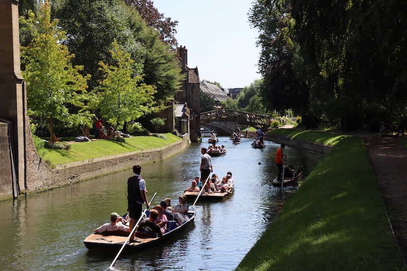 a lovely and crowded river with many people enjoying themselves, viewed during a cambridge punting tour