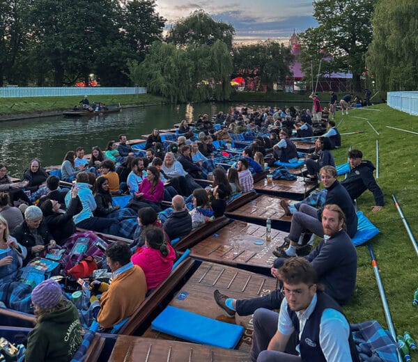 Crowded punts moored along the riverbank as guests wait for the May Ball fireworks in Cambridge