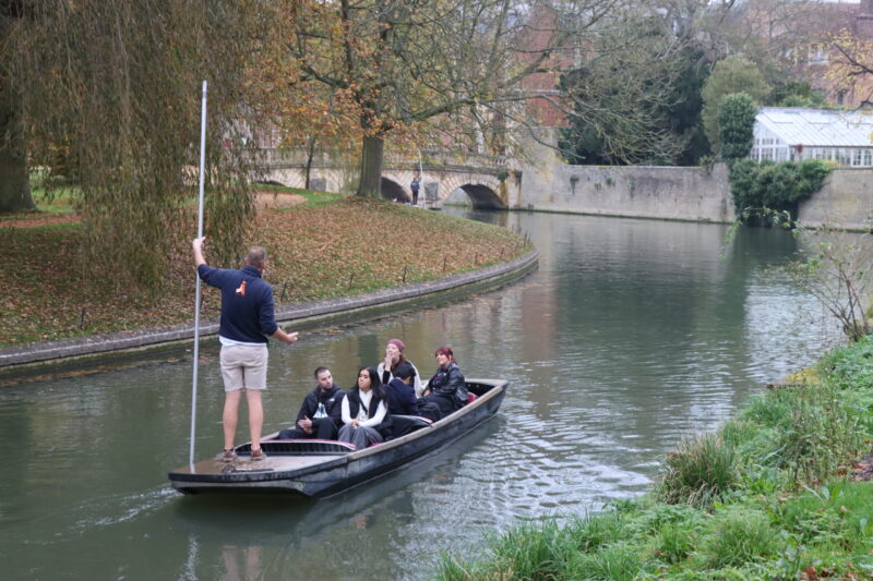 customers listening to their punting chauffeur on a punting boat on the River Cam by St Johns College Cambridge