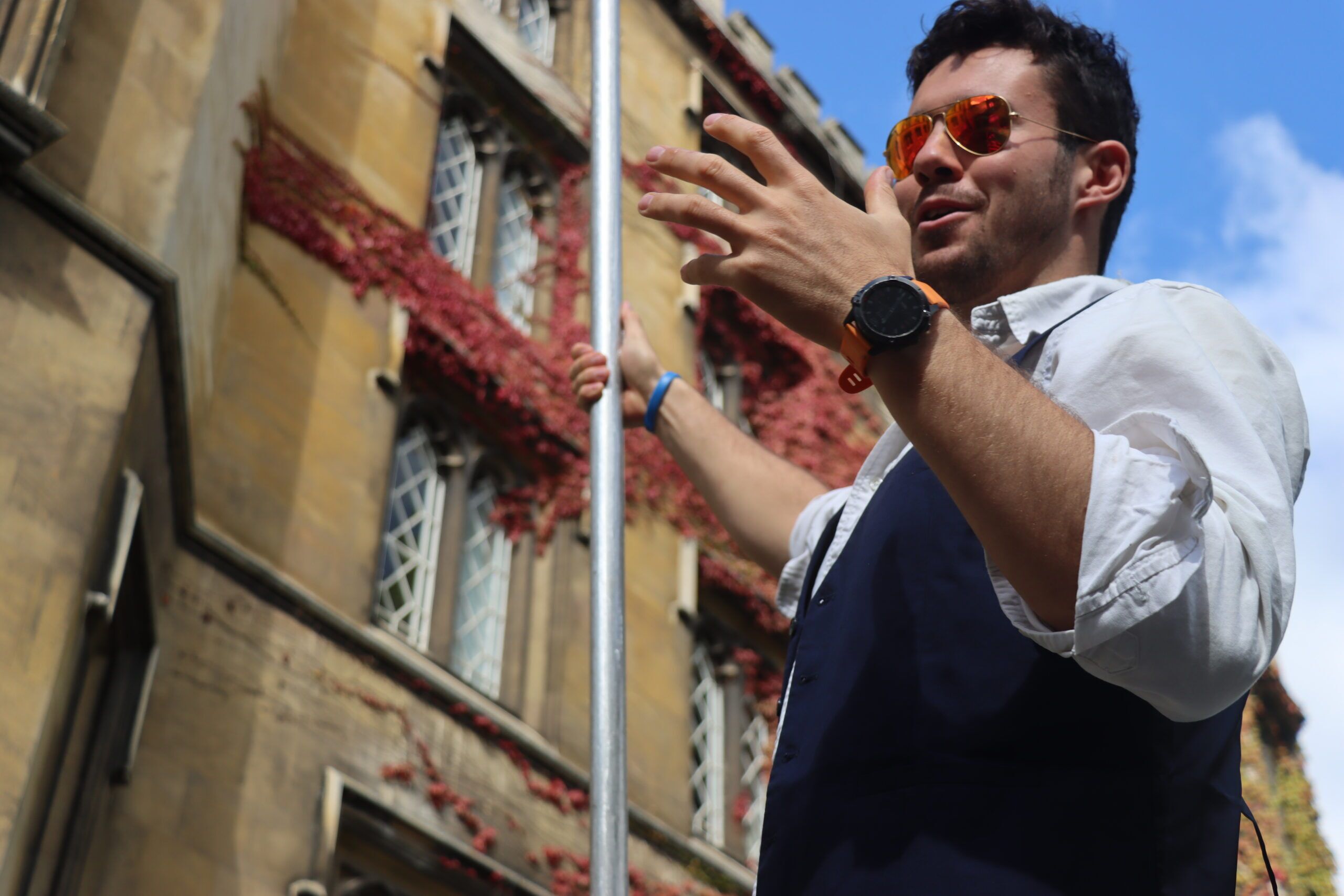 a tour guide at Let's Go Punting with St Johns College Cambridge in the background as he explains the sights
