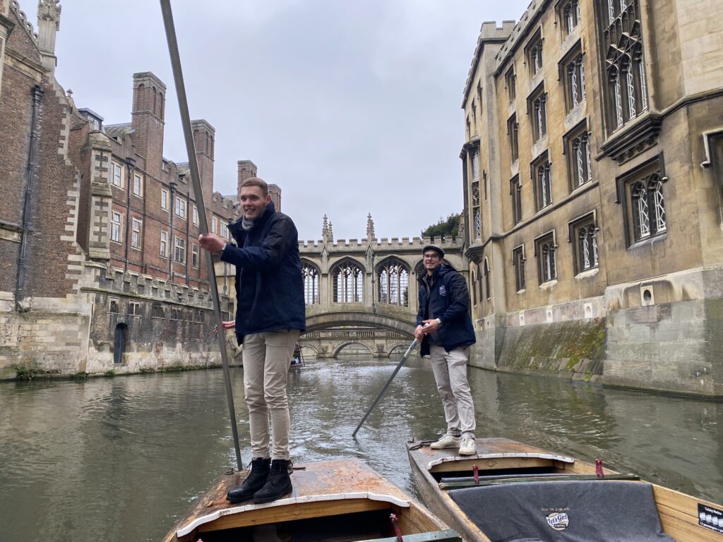 Two punt chauffeurs steering through St John's College towards the Bridge of Sighs.