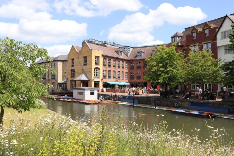 Quayside in Cambridge with punts moored along the River Cam beside riverside buildings.