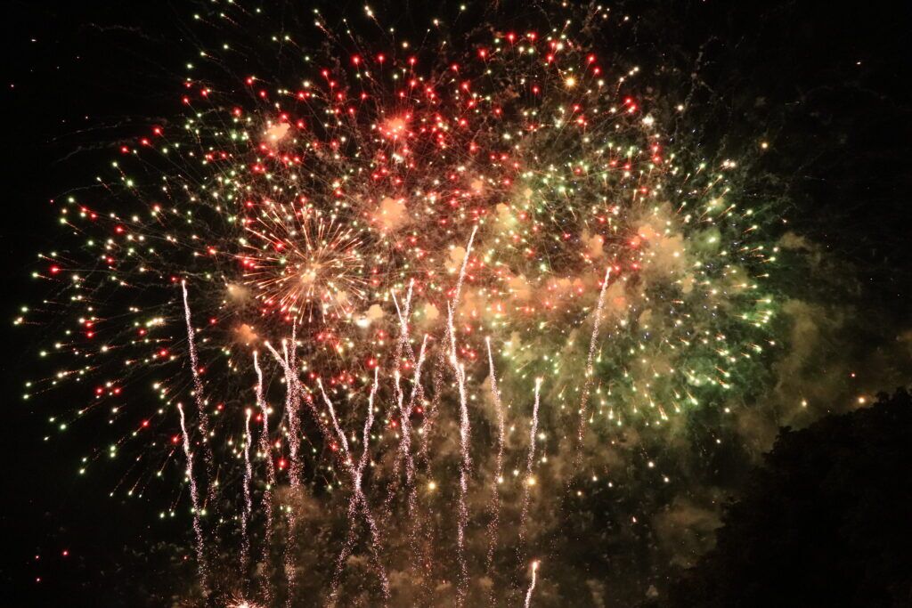 Red and green fireworks bursting across the night sky at a Cambridge Bonfire Night display.