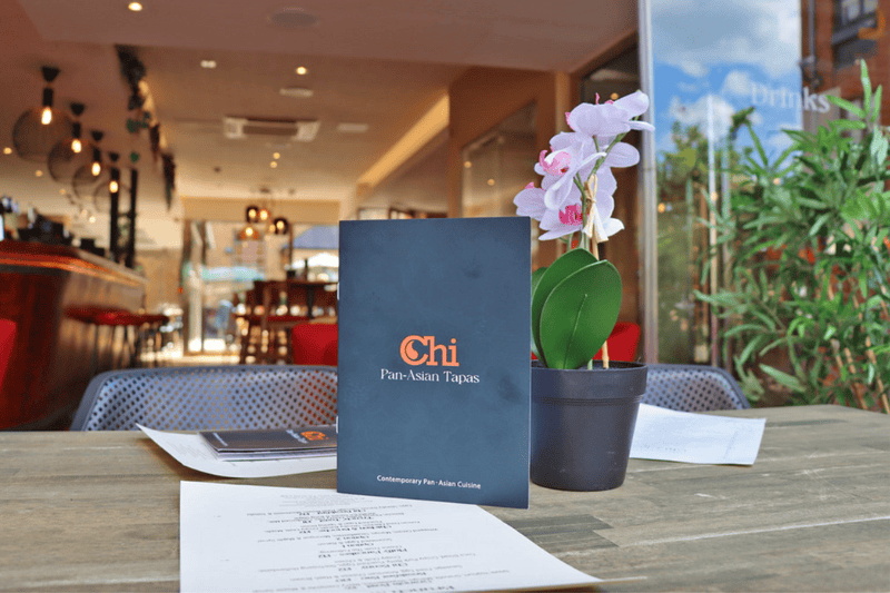 Chi Pan-Asian Tapas menu and orchid on a table inside the Cambridge restaurant.