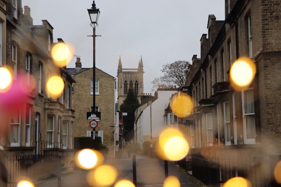 Cambridge street with festive bokeh lights looking towards the tower of Great St Mary's Church.