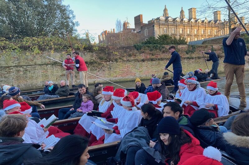 Carol singers in Santa hats on punts along the River Cam for Christmas Carols on the River.
