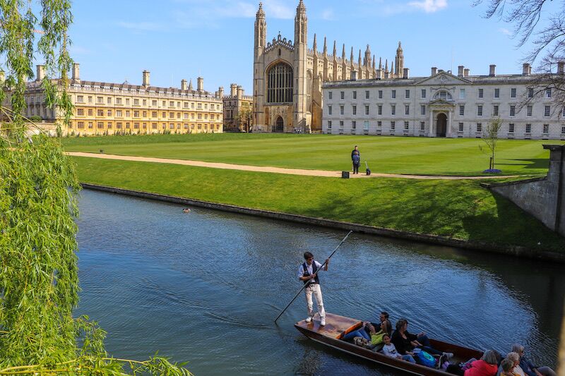 Punt chauffeur steering a tour along the River Cam with King's College Chapel across the lawns.