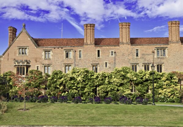 Historic stone building of Magdalene College, Cambridge, behind a flowering garden and lawn