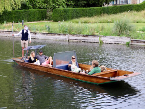 Shared punt divided into screened sections carrying separate groups on the River Cam.