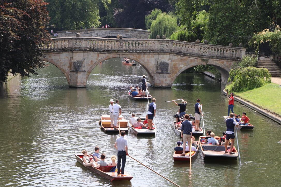 Many punts on the River Cam in front of Clare Bridge on a busy summer day of punting in Cambridge