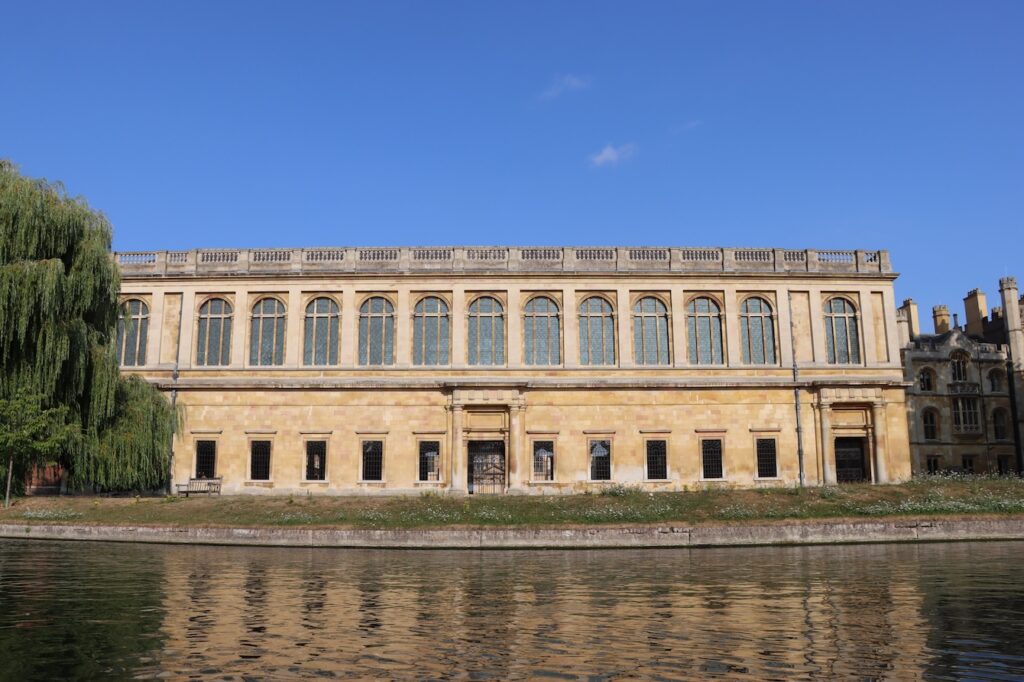 Sir Christopher Wren's library at Trinity College reflected in the River Cam under blue sky