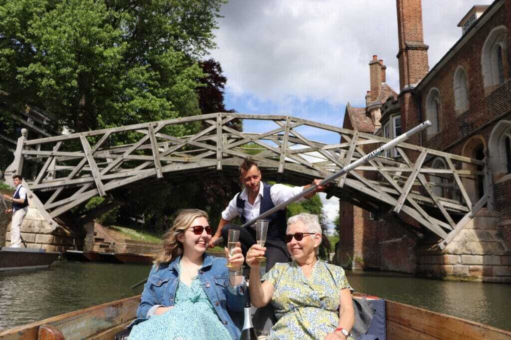 Mother and daughter raising a glass on a punt tour beneath the Mathematical Bridge at Queens' College